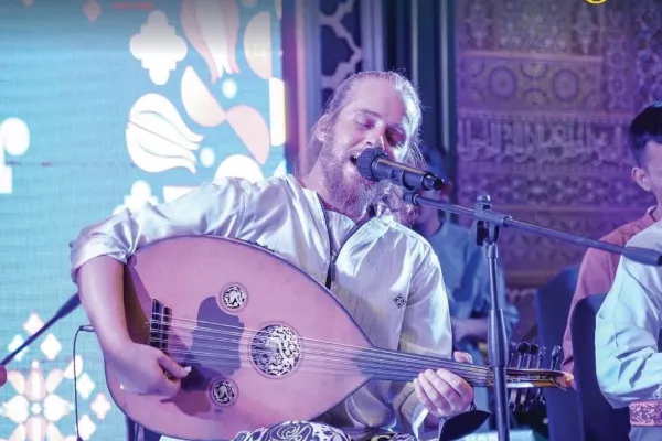 A man singing and a man looking at an art piece in an exhibition
